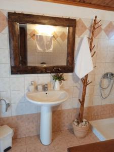 ein Badezimmer mit einem Waschbecken, einem Spiegel und einem Baum in der Unterkunft The old stone house in Paramythia