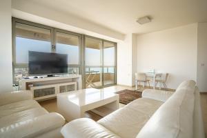 a living room with white furniture and a flat screen tv at Luxury Apartments Blue Wave in Ashdod