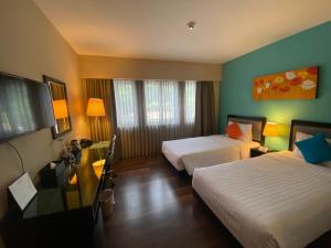 a hotel room with two beds and a television at The Brunei Hotel in Bandar Seri Begawan