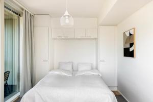 a bedroom with a white bed and a window at Kotimaailma Apartments Loimu III in Oulu