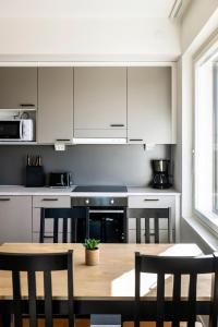 a kitchen with white cabinets and a wooden table at Kotimaailma Apartments Loimu III in Oulu
