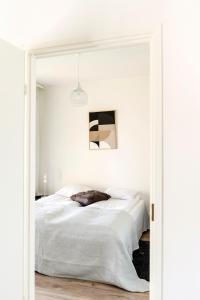 a white bedroom with a bed and a mirror at Kotimaailma Apartments Loimu V in Oulu
