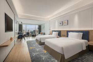 a hotel room with two beds and a television at voco Guangzhou Shifu, an IHG Hotel - Free shuttle between hotel and Exhibition Center during Canton Fair & Exhibitor registration Counter in Guangzhou