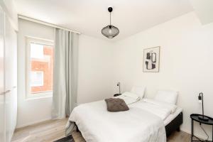 a white bedroom with a bed and a window at Kotimaailma Apartments Loimu II with Private Sauna in Oulu