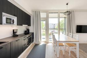 a kitchen with black cabinets and a table with chairs at Kotimaailma Apartments Loimu II with Private Sauna in Oulu