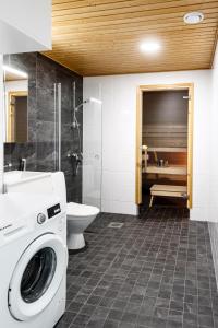 a bathroom with a washing machine and a toilet at Kotimaailma Apartments Loimu II with Private Sauna in Oulu +12 photos
