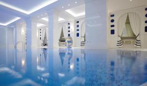 a swimming pool with blue water in a white room at Pomegranate Wellness Spa Hotel in Nea Potidaea