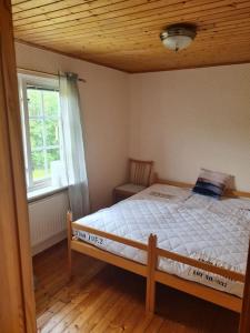 1 dormitorio con 1 cama en una habitación con ventana en Trevlig och havsnära stuga, en Glommen