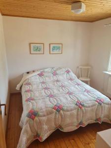 a bedroom with a bed with a quilt on it at Trevlig och havsnära stuga in Glommen