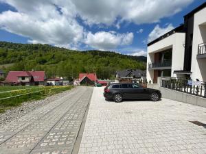 a car parked on a street next to a house at Apartament RELAKS w spokojnej okolicy - SUN&SPORT in Szczyrk