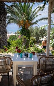 einen weißen Tisch und Stühle auf einer Terrasse mit einer Palme in der Unterkunft Kavos Hotel Naxos in Agios Prokopios