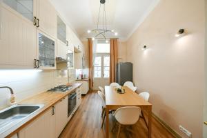 cocina con armarios blancos, mesa y sillas en Stunning Charles Bridge Apartment, en Praga