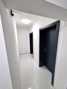 a hallway with two black doors and a white tile floor at Motel Gas-Petrol in Brčko