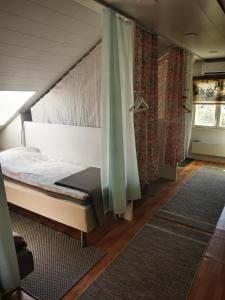a bedroom with a bed and curtains and a rug at Guesthouse Siskonpeti in Korppoo