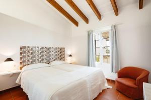 Agroturismo Son Triay في فيريريس: غرفة نوم بيضاء بسرير وكرسي