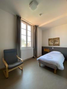 um quarto com uma cama, uma cadeira e uma janela em Hotel Saint Louis Beaulieu - Bordeaux em Bordéus