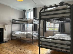 a room with three bunk beds and a fireplace at Cricketers Hostel in London