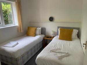 2 Einzelbetten in einem Zimmer mit Fenster in der Unterkunft Family Bungalow sleeps 4 in Wellington