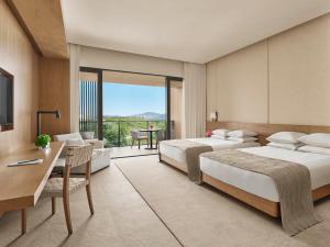 a hotel room with two beds and a desk and a table at The Sanya EDITION in Sanya