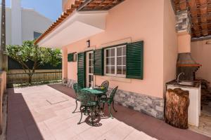 a patio with a table and chairs in front of a house at ALTIDO Superb house with garden and patio in Charneca