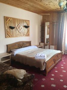 a bedroom with a large bed with a wooden headboard at Guest house Zatishniy dvir in Yaremche