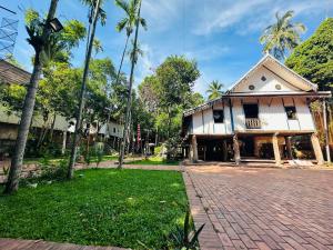 a house with a brick driveway and palm trees at Thatsaphone Hotel in Luang Prabang