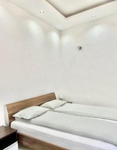 a bedroom with a bed with white walls at SMART GuestHouse in Oradea