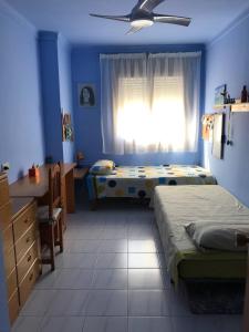 1 dormitorio con 2 camas, escritorio y ventana en Pis ampli i còmode a 5 min de l’Escala, en Bellcaire dʼEmpordà