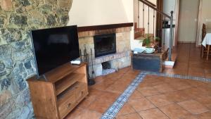 un salon avec une télévision et une cheminée dans l'établissement Casa rural La Casina, à Sariego