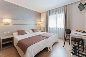 Cette chambre comprend un grand lit et une table. dans l'établissement Hotel & Aparthotel Cosmos, à Andorre-la-Vieille