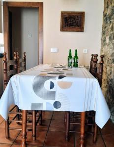 uma mesa com uma toalha de mesa branca com garrafas em Casa rural La Casina em Sariego