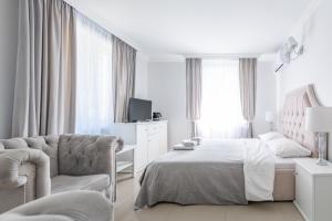 a white bedroom with a bed and a chair at Fryderyk in Krynica Morska