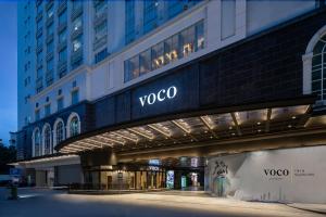 voco Guangzhou Shifu, an IHG Hotel - Free shuttle between hotel and Exhibition Center during Canton Fair & Exhibitor registration Counter في قوانغتشو: إطلالة على مبنى voco في الليل