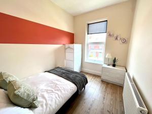 a bedroom with a bed with a red headboard and a window at 3 BDRM home 10mins from the city in Heaton