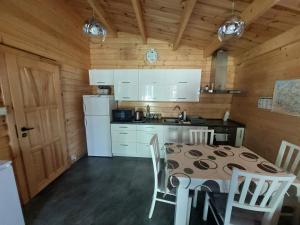 a kitchen with a table and white appliances in a cabin at Letniskowy domek z Bali in Myszyniec +28 photos
