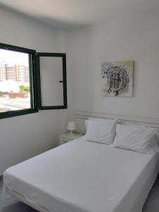 una camera con un letto bianco e due finestre di PLAYA DEL INGLES-MASPALOMAS a Playa del Ingles