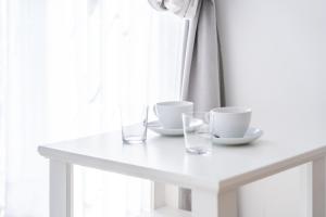 a white table with two cups and glasses on it at Fryderyk in Krynica Morska