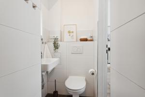 a white bathroom with a toilet and a sink at City Apartment! Bahnhof Kongress zentral ÖPNV in Kassel