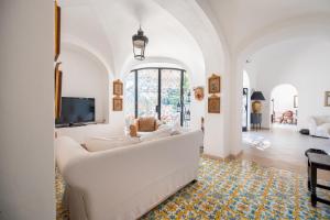 a living room with a white couch and a tv at Villa Petite Syrene by Elite Villas in Positano