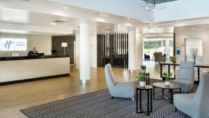 a lobby with chairs and a person at a counter at Holiday Inn Express Leigh - Sports Village, an IHG Hotel in Leigh