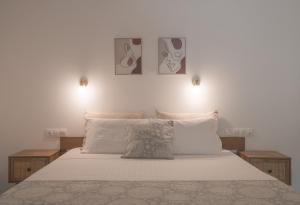 una camera con un letto bianco con due immagini sul muro di Levantes Hotel a Patitiri