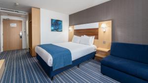 um quarto de hotel com uma cama e um sofá em Holiday Inn Express Leigh - Sports Village, an IHG Hotel em Leigh