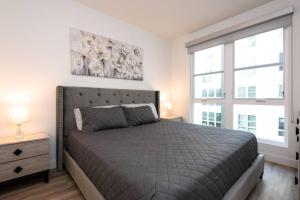 a bedroom with a large bed and two windows at Lux Apt with Rooftop pool by Convention Centr and Petco Park 40 in San Diego