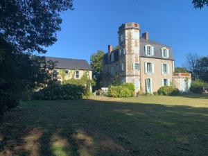 an old house with a tower on top of a field at Chateau pool house in Assat