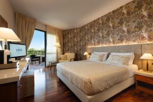 a bedroom with a bed and a desk and a television at Savoy Beach Hotel & Thermal Spa in Bibione