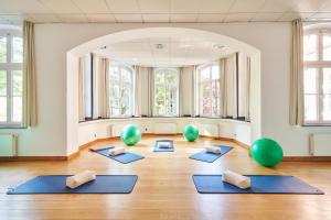 una sala de yoga con alfombras azules y pelotas de pilates verdes en Hotel Mutterhaus Düsseldorf, en Düsseldorf