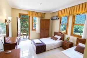 een slaapkamer met een bed, een bureau en ramen bij Yeşilkaya Hotel in Kayakoy