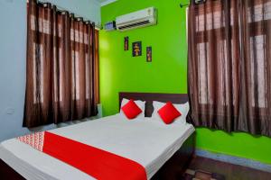 a bedroom with green walls and a bed with red pillows at Flagship Hotel Heaven Inn in Patna