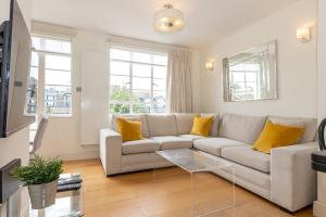 sala de estar con sofá blanco y almohadas amarillas en Bright & Spacious Top Floor Apartment in Chelsea, en Londres