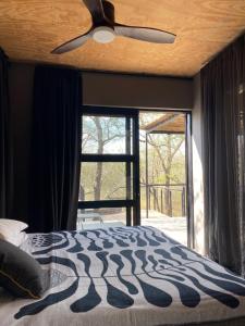 a bedroom with a ceiling fan and a large window at Terrapin Studio in Marloth Park